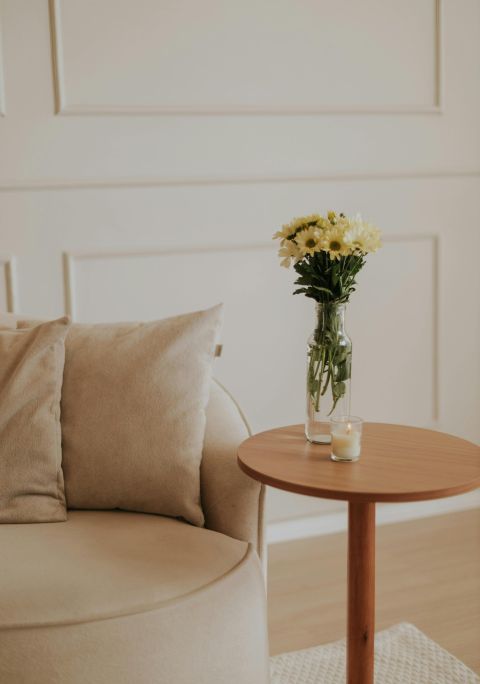 Serene minimalist living room interior featuring a cozy beige armchair and a vase of yellow flowers.
