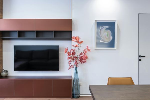 Contemporary TV set placed near cabinet and vase with flowers placed in stylish room with table in decorated apartment at home