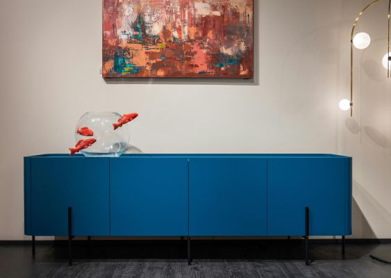 Contemporary interior featuring a fishbowl on a blue cabinet, vibrant wall art, and elegant lighting.